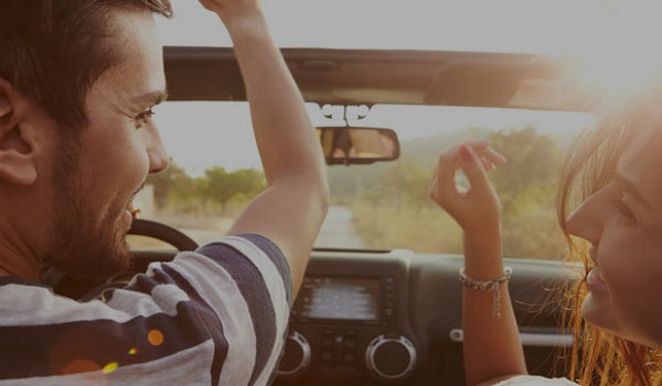Man and woman smiling in top down car
